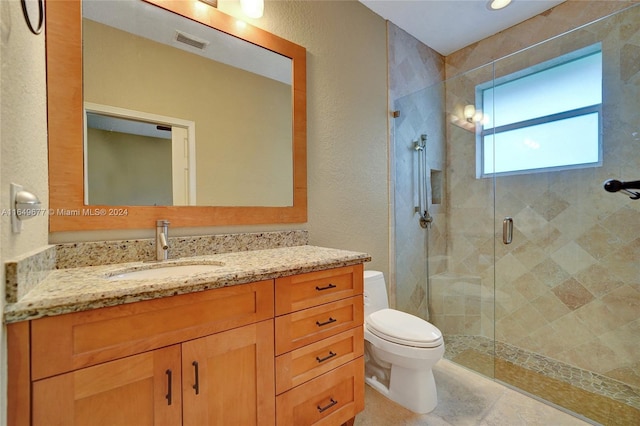 bathroom with a shower with door, vanity, toilet, and tile patterned flooring