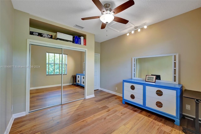 bedroom with a closet, ceiling fan, light hardwood / wood-style floors, and a textured ceiling