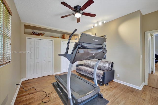 exercise room featuring a textured ceiling, light hardwood / wood-style flooring, ceiling fan, and rail lighting