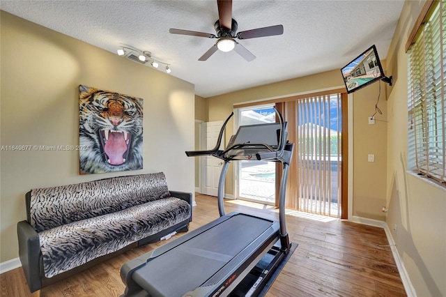 workout area with track lighting, a textured ceiling, hardwood / wood-style floors, and ceiling fan