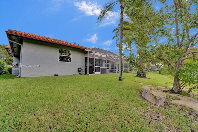 rear view of property featuring a lawn and a lanai