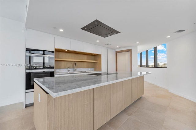 kitchen with light stone countertops, sink, stainless steel double oven, black electric stovetop, and a kitchen island