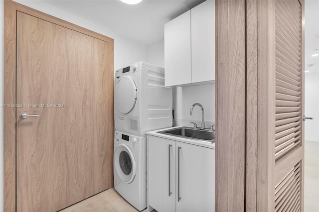 clothes washing area featuring sink, cabinets, and stacked washer and dryer