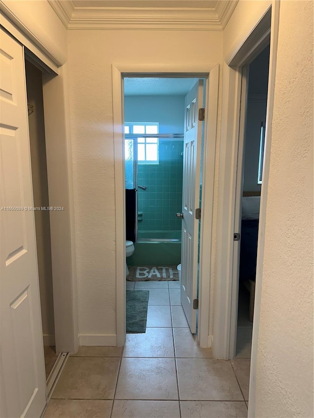 hall with ornamental molding and light tile patterned floors