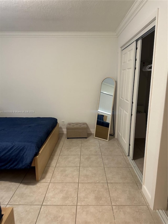 tiled bedroom featuring a textured ceiling, crown molding, and a closet