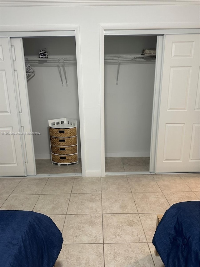 interior space with light tile patterned floors and multiple closets