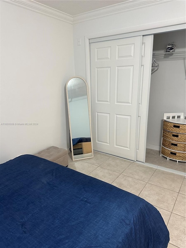 bedroom with a closet, ornamental molding, and light tile patterned floors