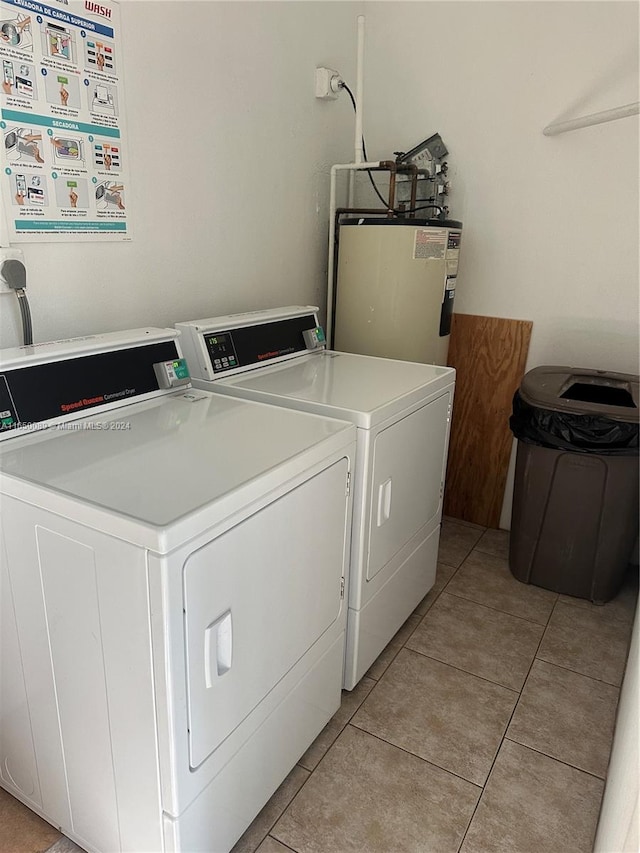 clothes washing area with light tile patterned floors, washer and clothes dryer, and water heater