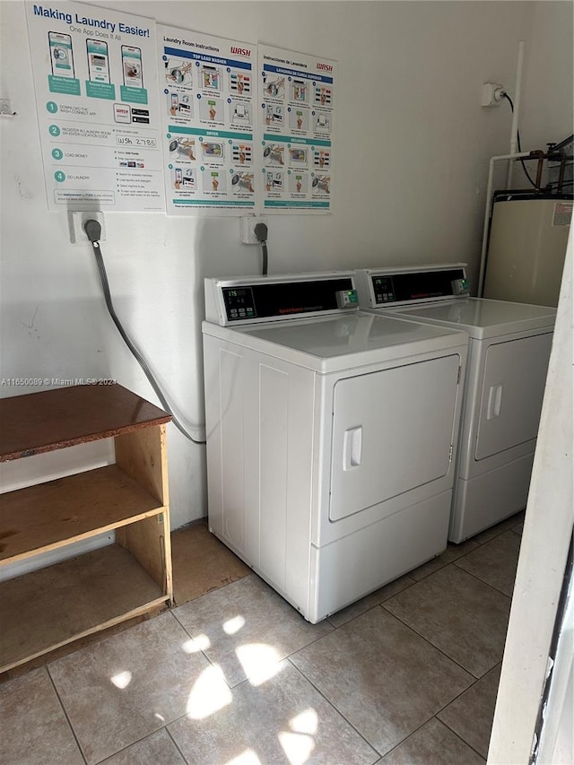 laundry area with gas water heater, washing machine and dryer, and light tile patterned floors