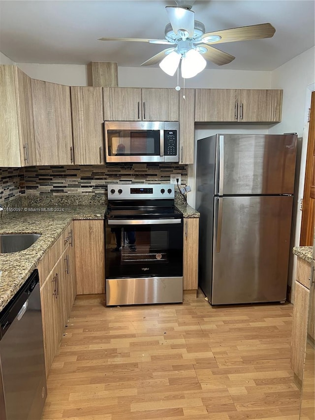 kitchen featuring backsplash, light stone countertops, sink, and appliances with stainless steel finishes