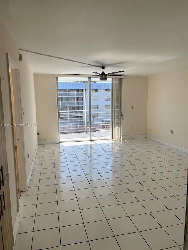 tiled spare room featuring ceiling fan and expansive windows