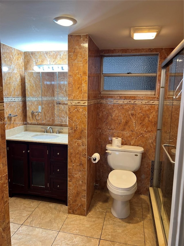 bathroom featuring an enclosed shower, vanity, toilet, and tile walls