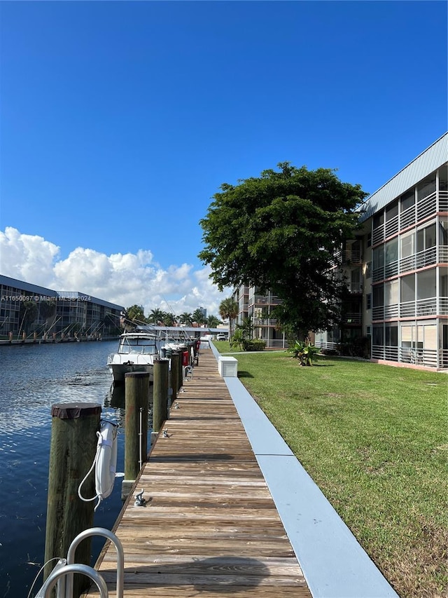 view of dock featuring a water view and a yard