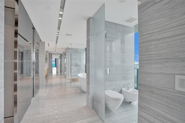 19575 Collins Ave Unit 33, Sunny Isles Beach, FL 33160 - full bathroom featuring a bidet, a stall shower, a soaking tub, toilet, and tile walls
