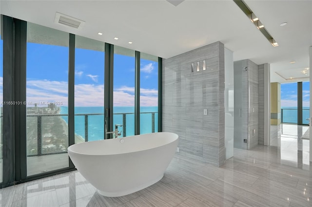 19575 Collins Ave Unit 33, Sunny Isles Beach, FL 33160 - bathroom featuring expansive windows, a water view, a soaking tub, tile patterned flooring, and tile walls