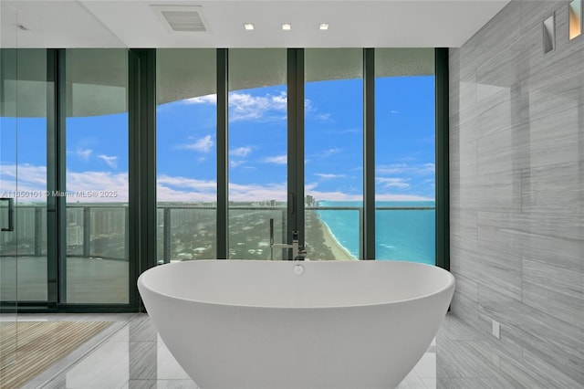 19575 Collins Ave Unit 33, Sunny Isles Beach, FL 33160 - bathroom with a freestanding tub, tile patterned flooring, a water view, tile walls, and expansive windows