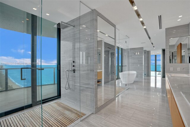 bathroom featuring a wall of windows, shower with separate bathtub, a water view, and tile patterned flooring