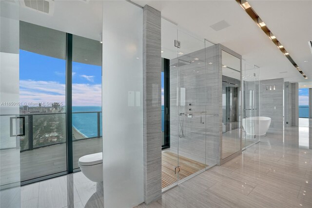 bedroom featuring a water view, expansive windows, access to exterior, and multiple windows