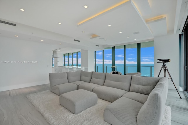 living room with a water view, expansive windows, sink, and light hardwood / wood-style flooring