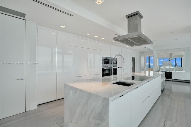 kitchen with island range hood, a large island, black electric stovetop, white cabinets, and sink