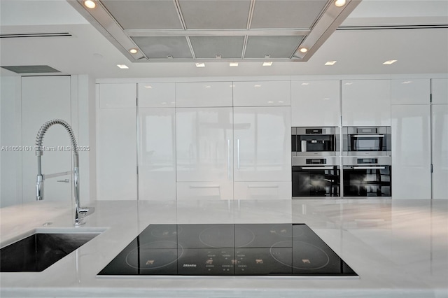 19575 Collins Ave Unit 33, Sunny Isles Beach, FL 33160 - kitchen featuring modern cabinets, a sink, black electric stovetop, white cabinetry, and stainless steel double oven