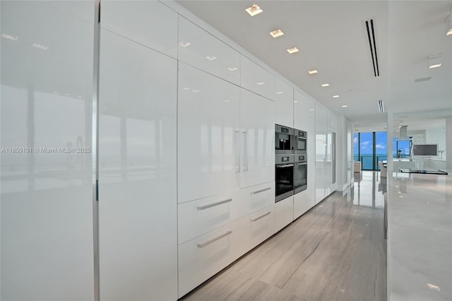 19575 Collins Ave Unit 33, Sunny Isles Beach, FL 33160 - kitchen with modern cabinets, white cabinetry, light wood-style floors, light stone counters, and expansive windows