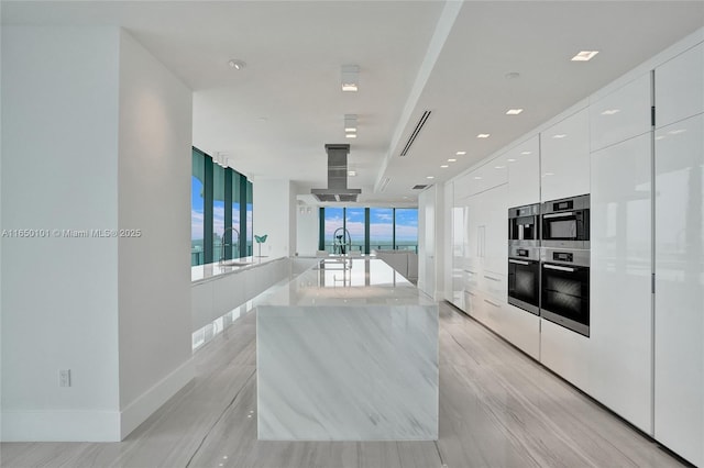 19575 Collins Ave Unit 33, Sunny Isles Beach, FL 33160 - kitchen featuring modern cabinets, white cabinets, stainless steel double oven, island exhaust hood, and light wood-style floors
