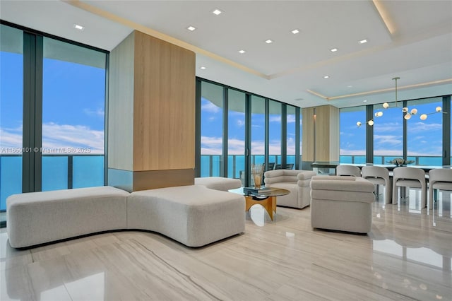 living room featuring a water view, expansive windows, an inviting chandelier, and a healthy amount of sunlight