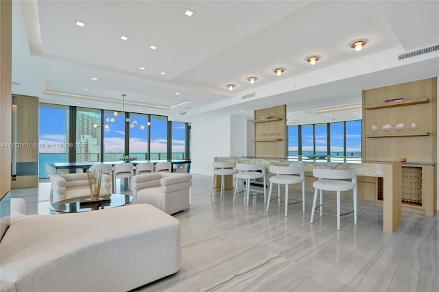 living room with a tray ceiling, expansive windows, and a water view