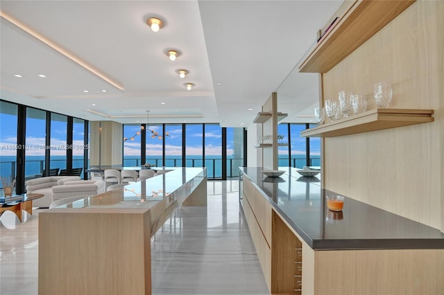 kitchen featuring floor to ceiling windows, light brown cabinetry, a water view, and a large island