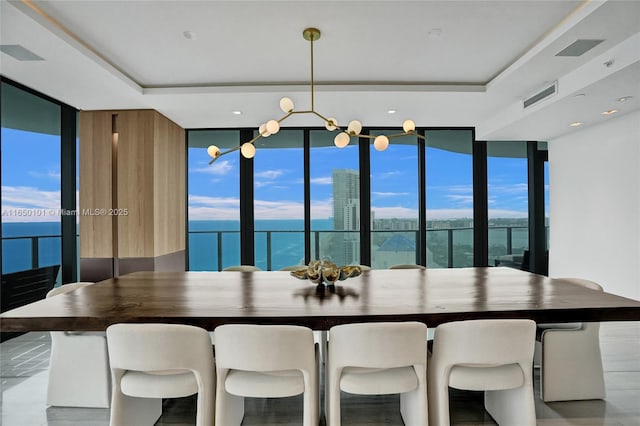 unfurnished dining area with a wall of windows, a water view, and a tray ceiling