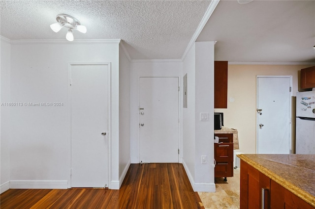 kitchen with a textured ceiling, crown molding, white fridge, and light hardwood / wood-style floors