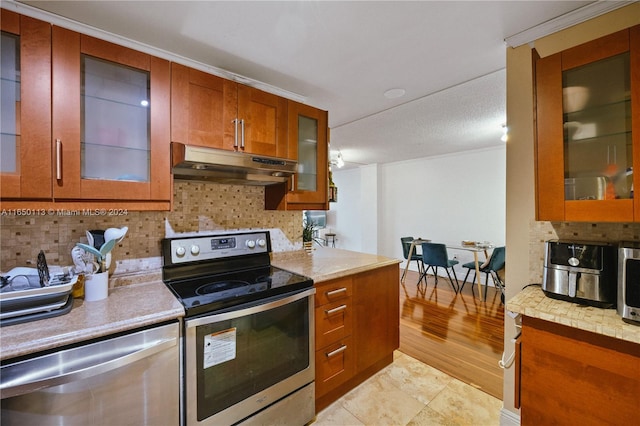 kitchen featuring light wood-type flooring, appliances with stainless steel finishes, ornamental molding, and backsplash