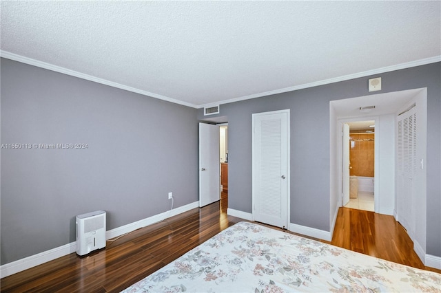 bedroom featuring a closet, hardwood / wood-style flooring, crown molding, and a textured ceiling