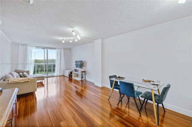 dining space featuring ornamental molding, hardwood / wood-style flooring, a textured ceiling, and rail lighting