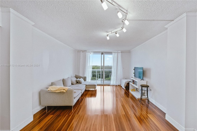 living room featuring a textured ceiling, ornamental molding, dark hardwood / wood-style flooring, and track lighting