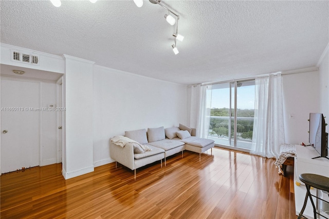 living room with a textured ceiling, rail lighting, hardwood / wood-style floors, and crown molding