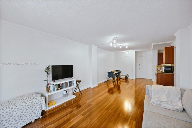 living room with a textured ceiling, light hardwood / wood-style flooring, ornamental molding, and track lighting