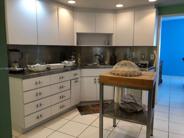 kitchen with light tile patterned flooring, sink, decorative backsplash, and white cabinets