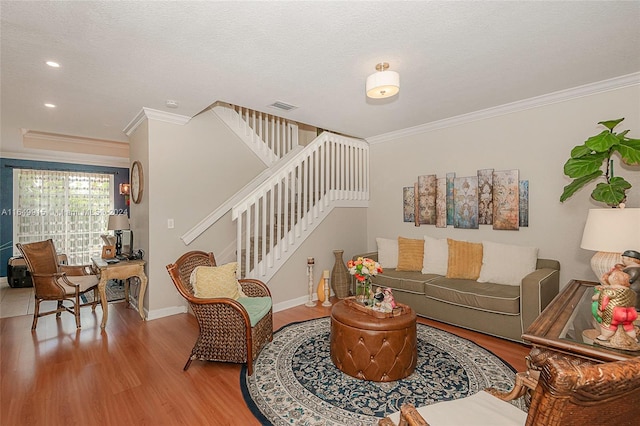 living room with wood-type flooring, a textured ceiling, and ornamental molding