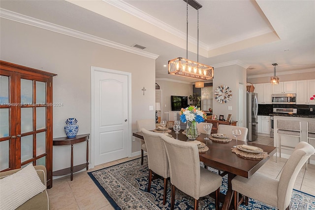 tiled dining space featuring ornamental molding and a raised ceiling