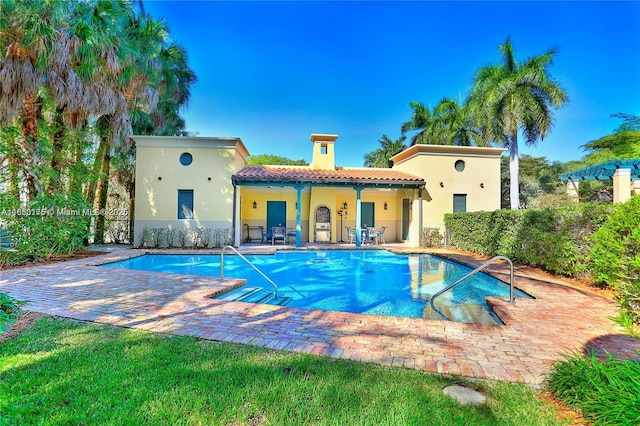 back of house with a tiled roof, a patio area, an outdoor pool, and stucco siding