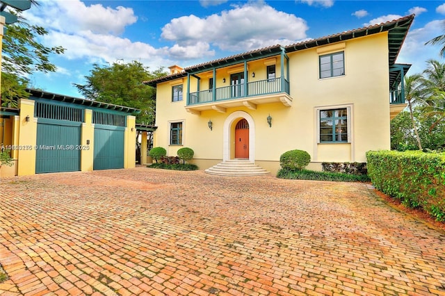 mediterranean / spanish-style home featuring stucco siding, a balcony, and fence