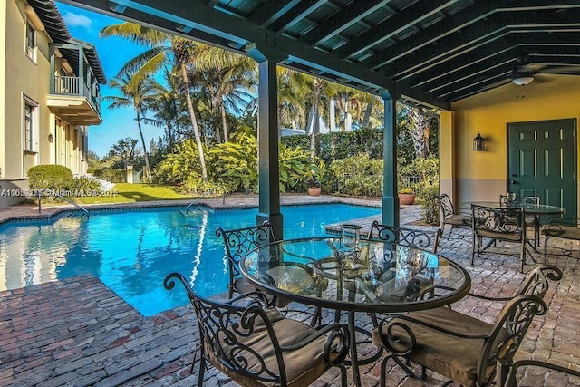 outdoor pool with a patio, outdoor dining space, and a ceiling fan