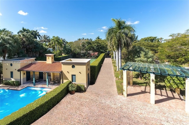 rear view of house with an outdoor pool, stucco siding, a tile roof, and a patio area