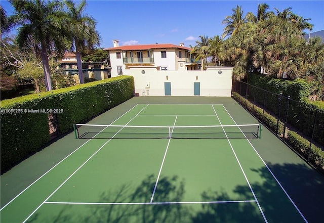 view of tennis court with community basketball court and fence