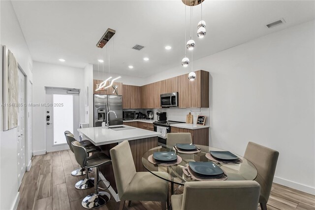 kitchen with hanging light fixtures, appliances with stainless steel finishes, and light hardwood / wood-style flooring