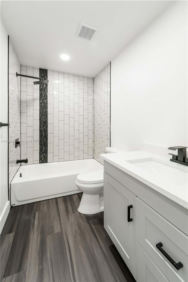 full bathroom featuring tiled shower / bath, vanity, toilet, and hardwood / wood-style floors