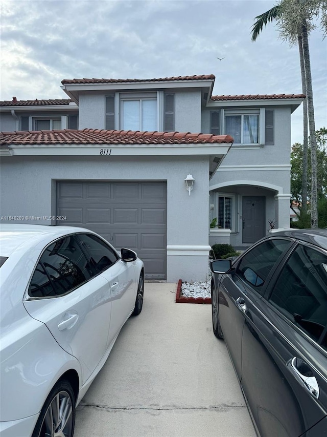 view of front facade featuring a tiled roof, stucco siding, an attached garage, and concrete driveway