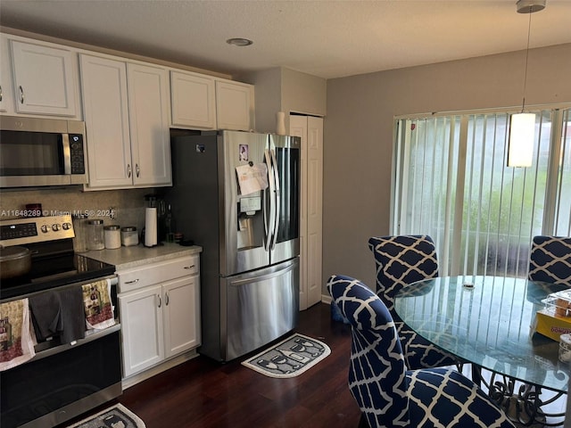 kitchen with dark wood-type flooring, decorative light fixtures, light countertops, stainless steel appliances, and white cabinetry